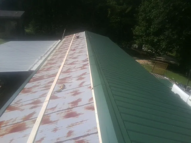 Old rusted panels beside newly installed green metal roofing — Wind Damage Roof Repair by Roofing Brothers in Woodstock